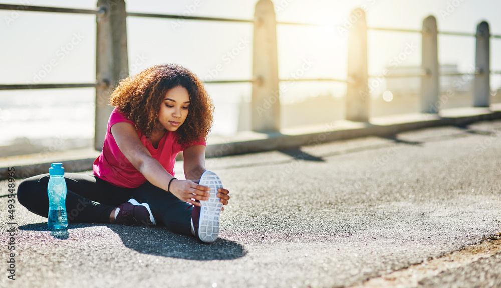 Gotta keep those muscles loose. Shot of a sporty young woman doing warmup exercises outdoors.