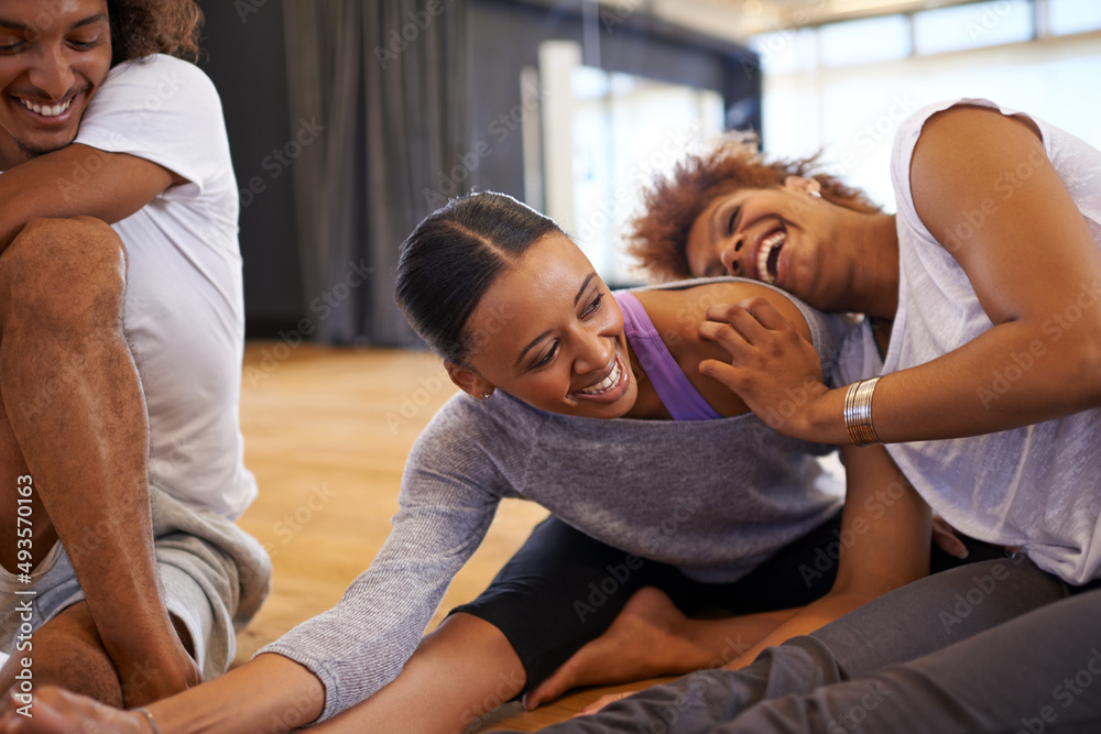 Warming up together makes it more fun. Shot of three happy young women dancers stretching on the flo