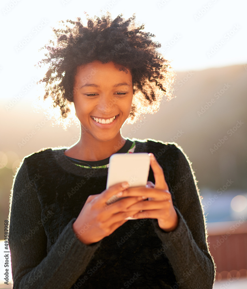 Sending out some sunshine. Shot of an attractive young woman sending a text message while walking ou