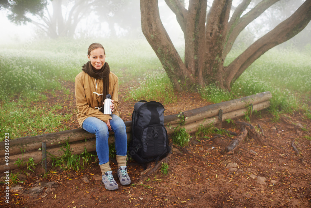 在美丽的环境中休息。一位年轻的女徒步旅行者坐在一棵树旁的肖像