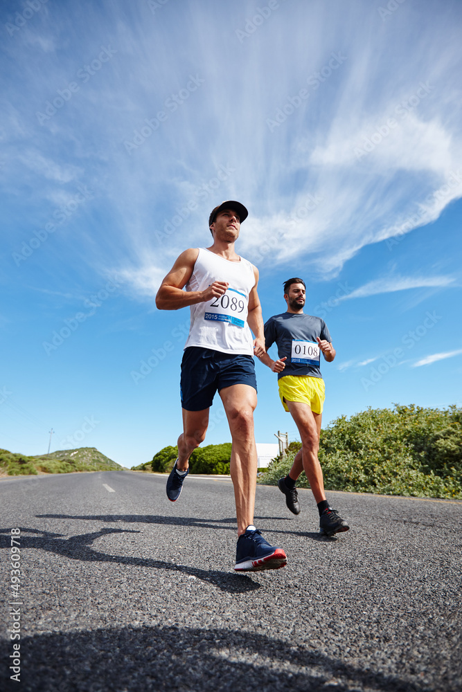 Hes catching up. Shot of a group of young men running a marathon.