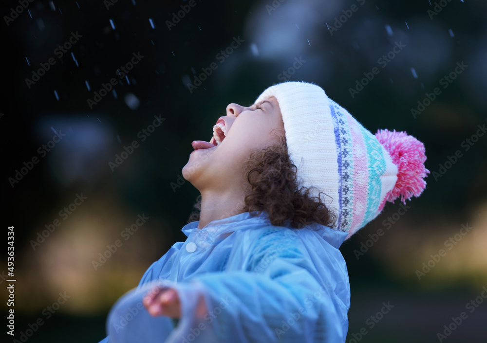 每个人都试图用嘴接住雨滴。一个可爱的小女孩独自站在外面的照片