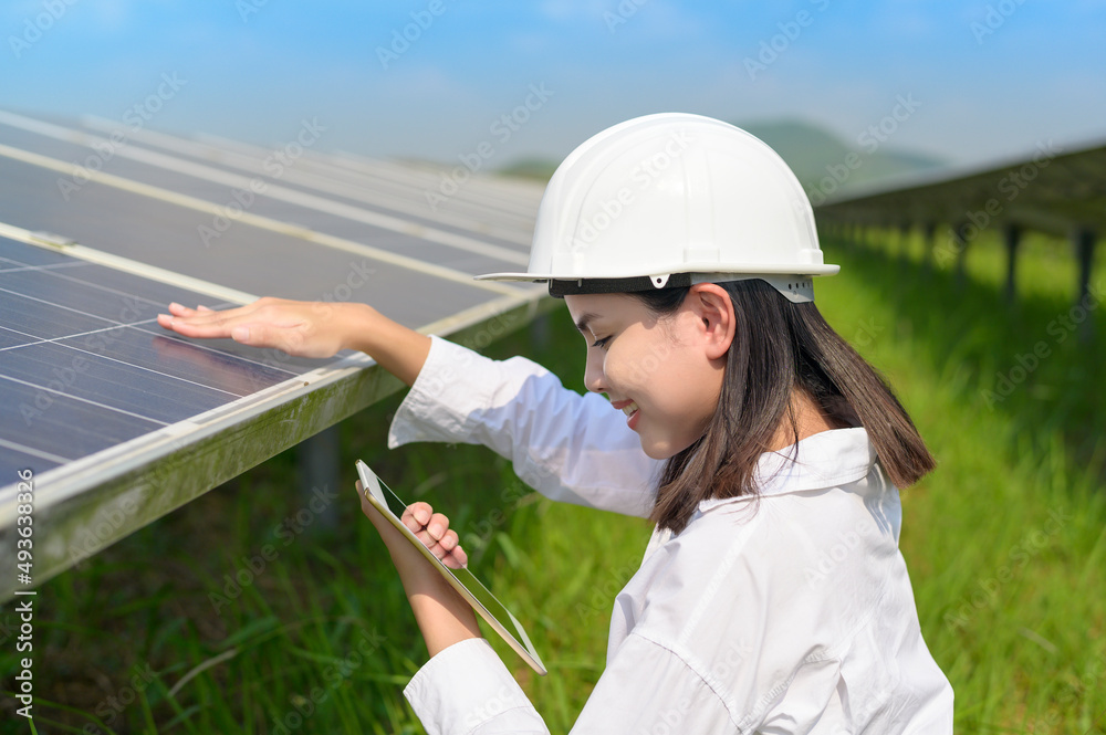 A female engineer wearing helmet in Photovoltaic Cell Farm or Solar Panels Field, eco friendly and c