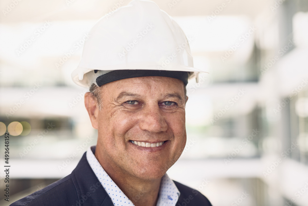 Geared up to start building. Portrait of a cheerful mature businessman standing in an office while l