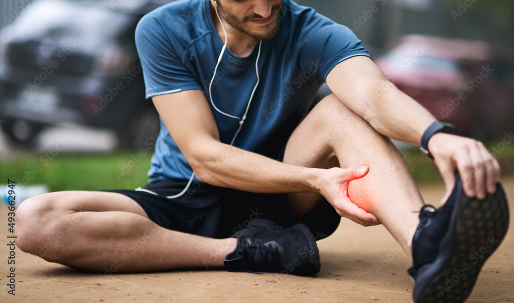 This injury calls for a timeout. Shot of a sporty young man holding his calf in pain while exercisin