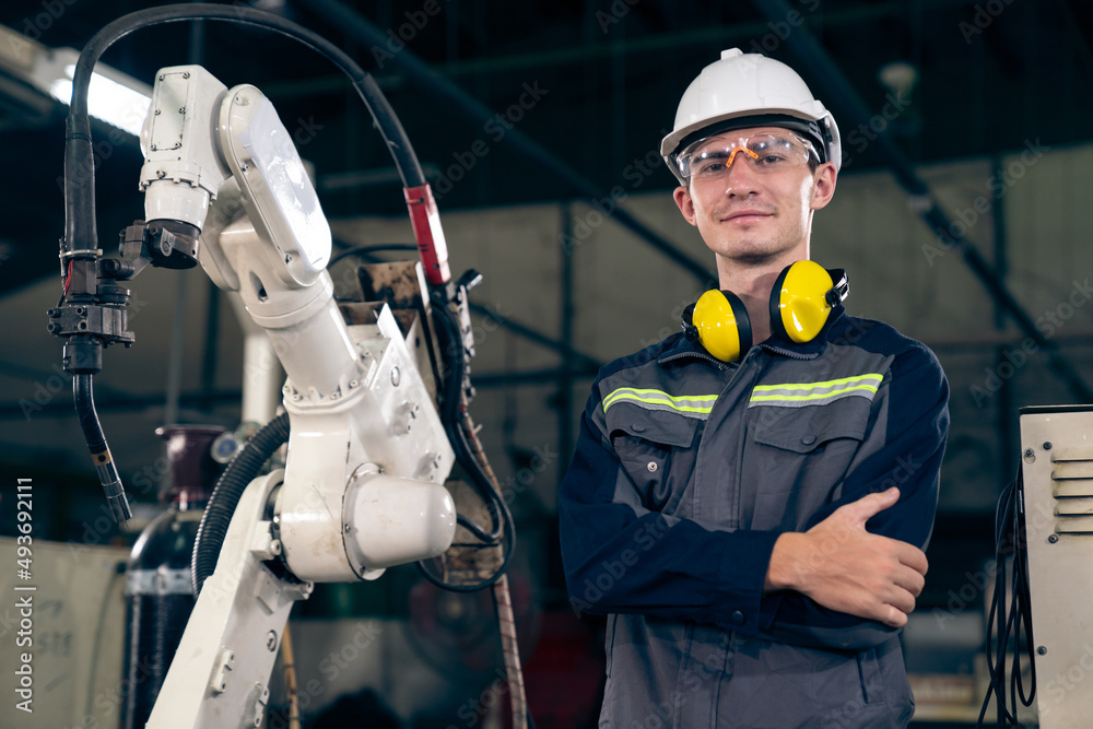 Young factory worker working with adept robotic arm in a workshop . Industry robot programming softw