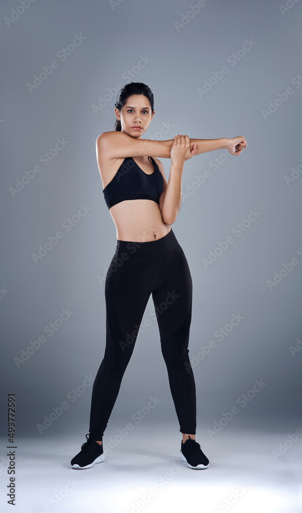 Stretching out before the real workout begins. Full length shot of a sporty young woman standing and