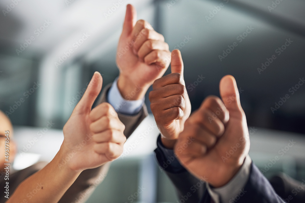 Thumbs up all round. Closeup shot of a group of businesspeople giving thumbs up together.