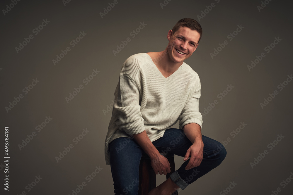 Where does he get his confidence from. Studio portrait of a cheerful young man seated against a grey