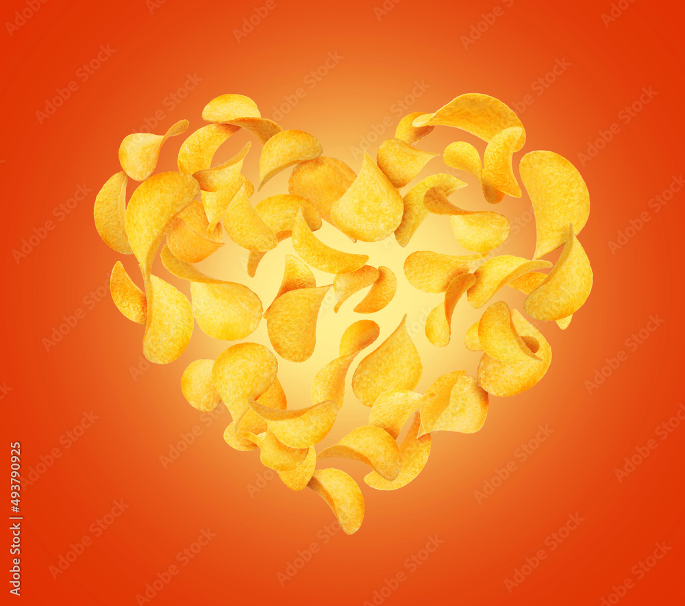 Potato chips in the air in the shape of a heart on a red background