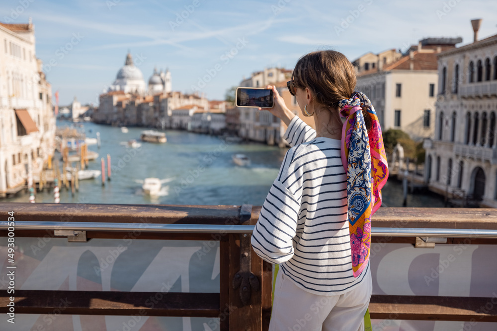 Young woman photographing o nphone beautiful view on Grand Canal from Academy bridge in Venice. Idea