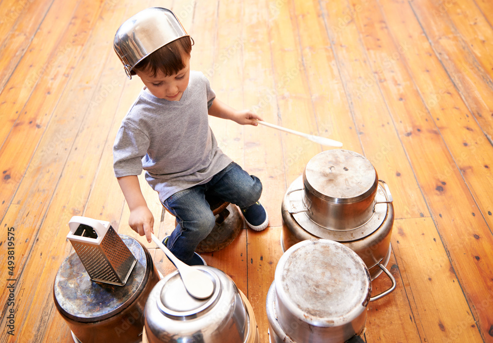 Kids rock. Shot of an adorable little boy drumming on pots and pans.