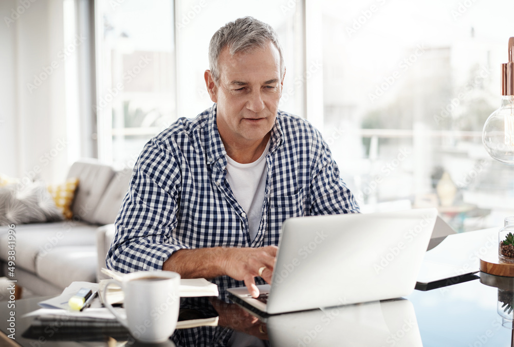 I have some emails to catch up to. Shot of a mature man working on a laptop at home.