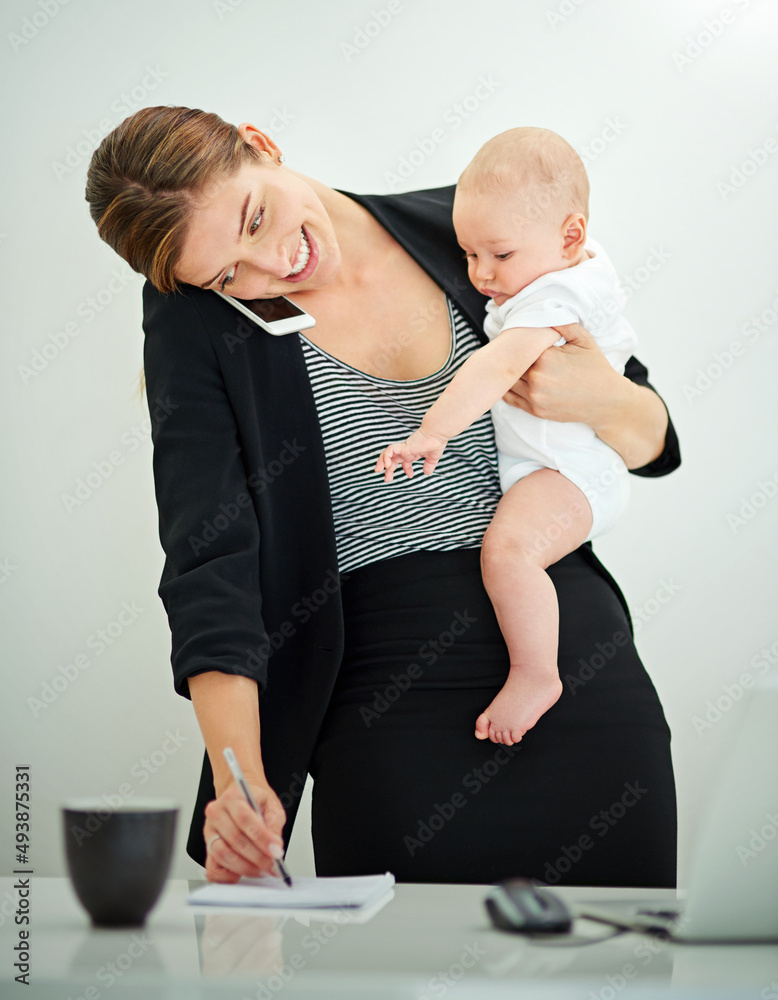 养育一家企业和一个婴儿。一位成功的年轻女商人抱着她可爱的婴儿b的照片