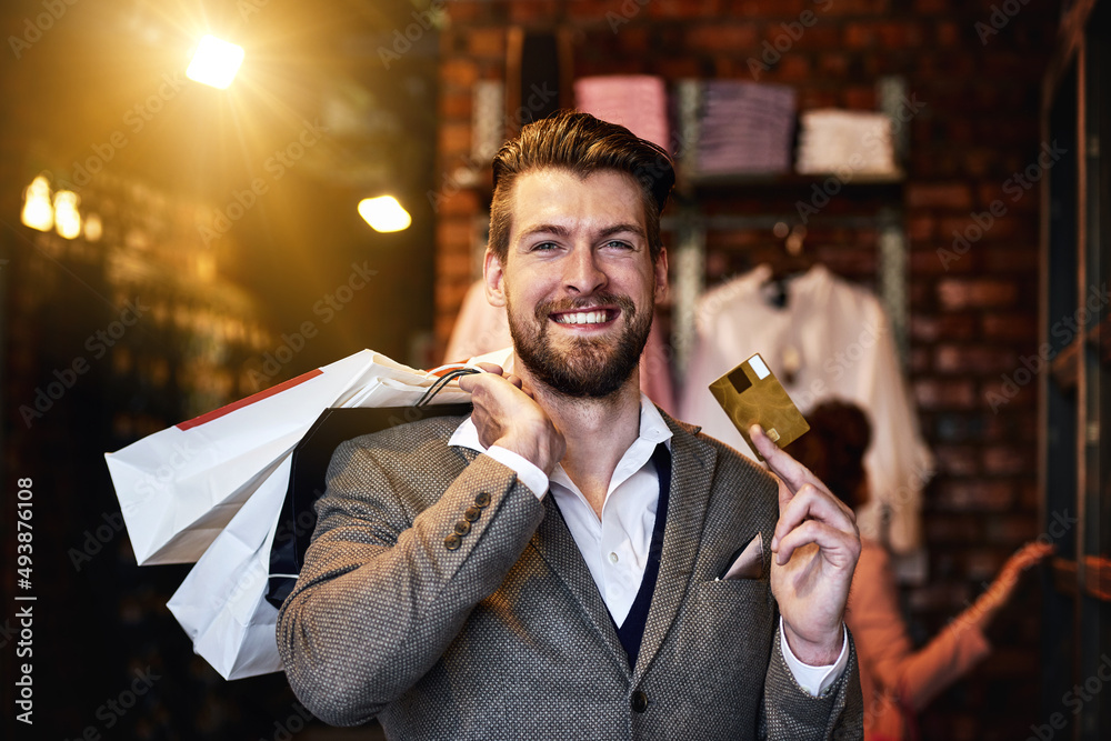 I got it on credit. Shot of a man holding up his credit card while out shopping.