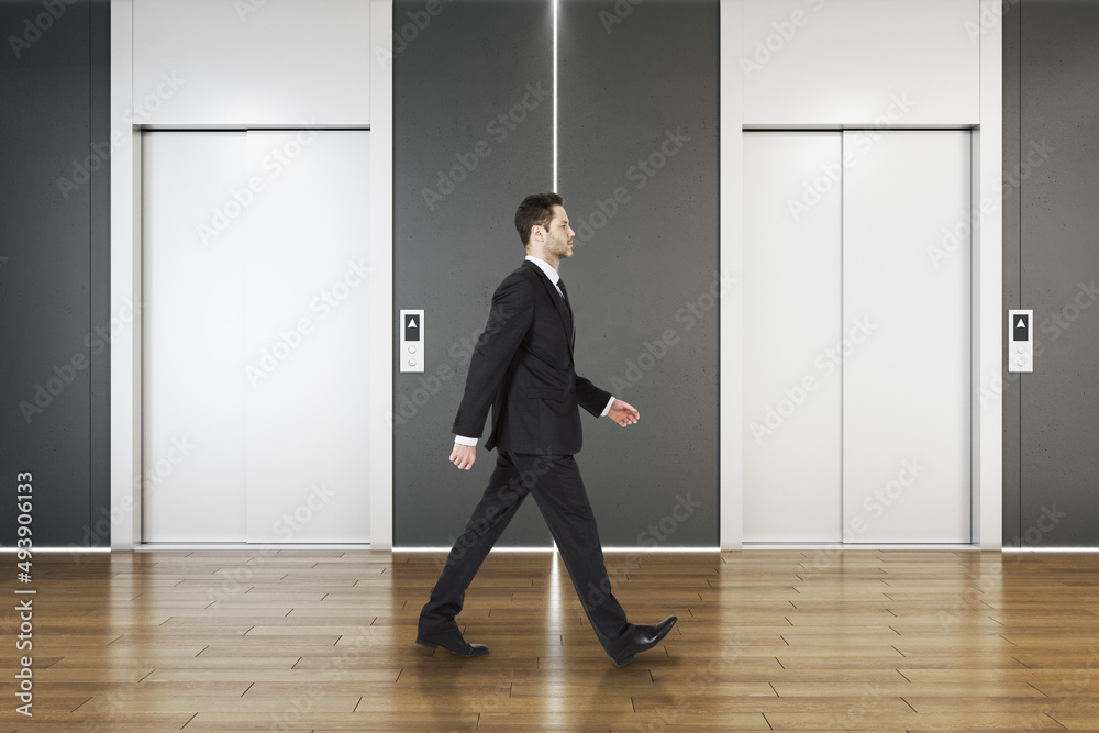 Man in modern concrete interior with elevators and wooden parquet flooring. Lift, lobby and start up