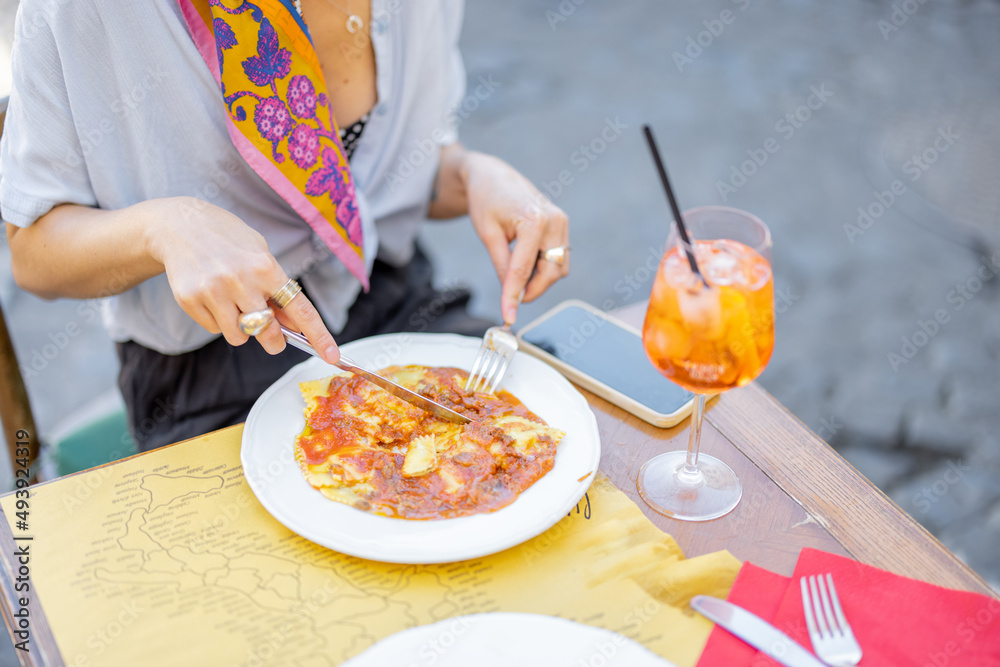 女人在户外餐厅吃意大利肉酱饺子，喝雪碧Aperol，特写