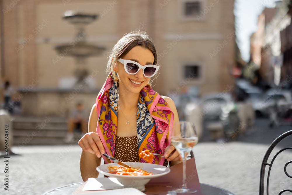 在罗马街头的餐厅吃意大利面食和喝葡萄酒的女人。意大利的概念