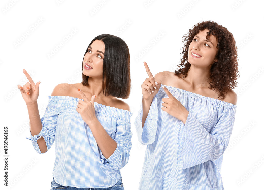 Young sisters pointing at something on white background