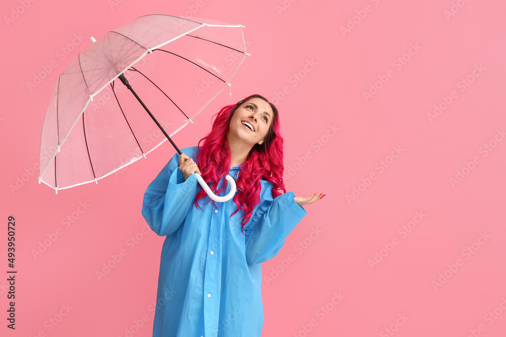 美丽的女人穿着雨衣，颜色背景上带着雨伞