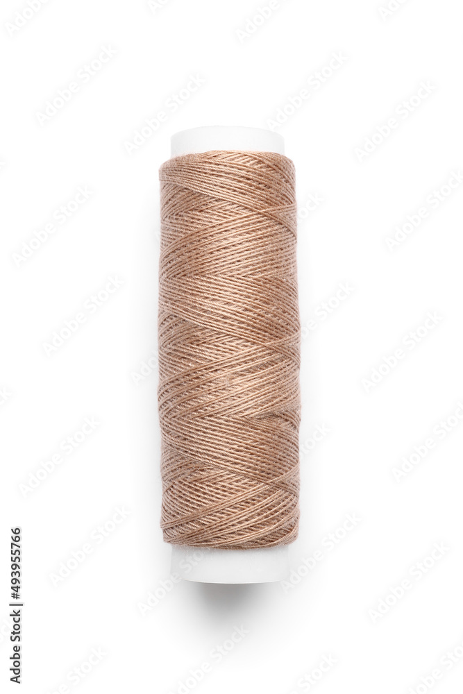 Beige sewing thread spool on white background