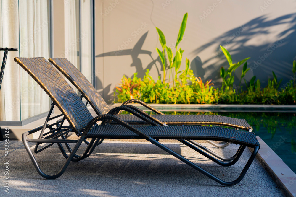 rattan bench standing next to swiming pool with small garden freshness environment background,relax 