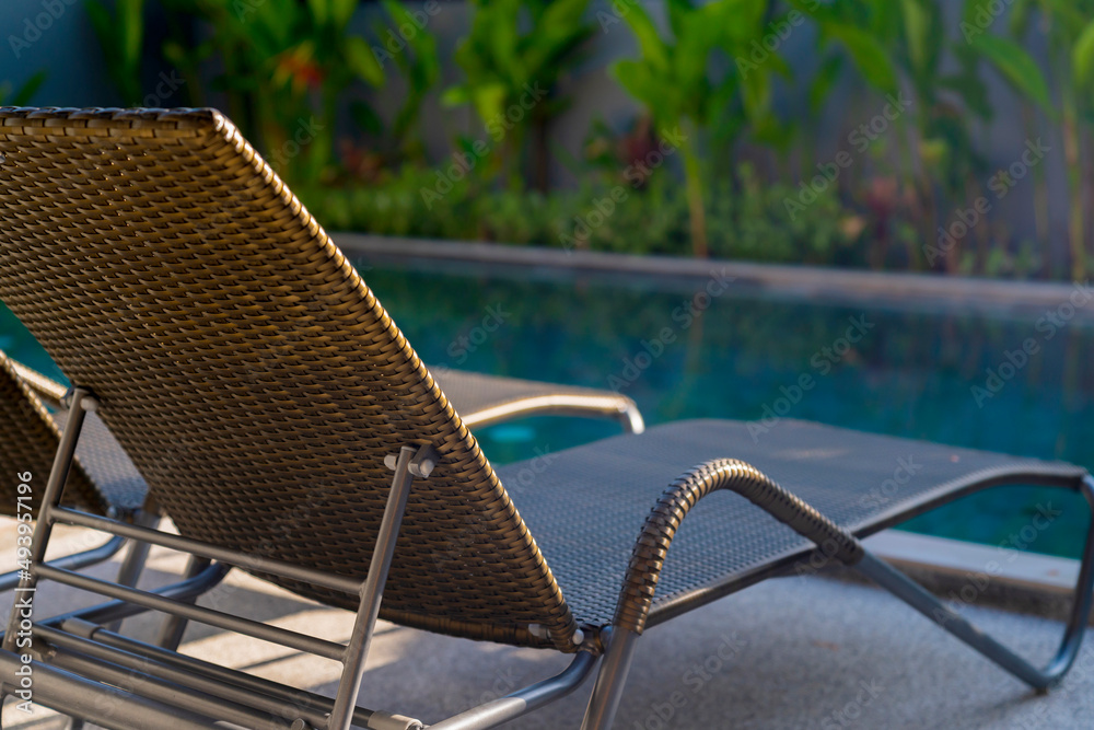 rattan bench standing next to swiming pool with small garden freshness environment background,relax 