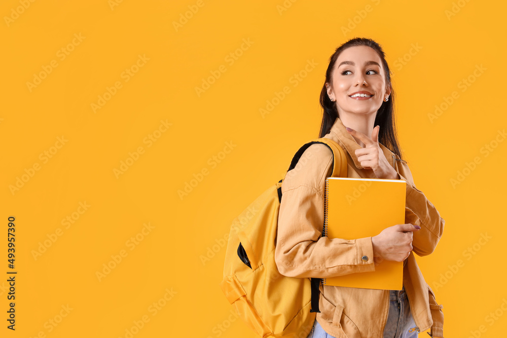 Portrait of beautiful female student showing something on color background