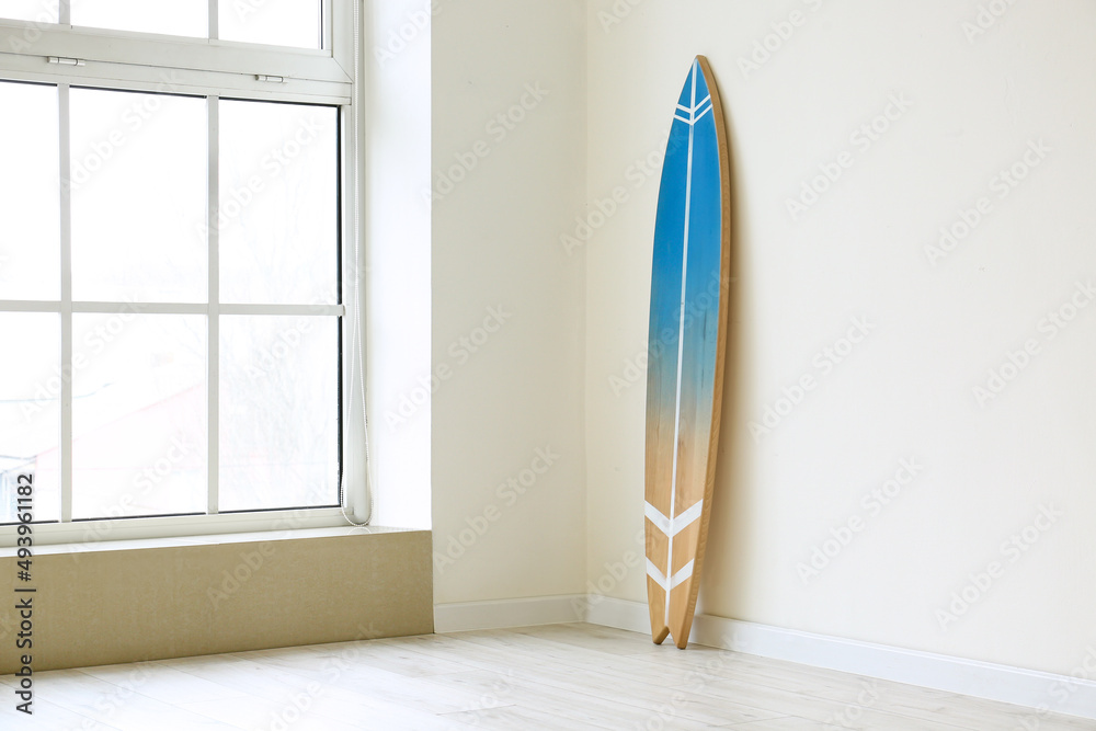 Surfboard in empty room near window