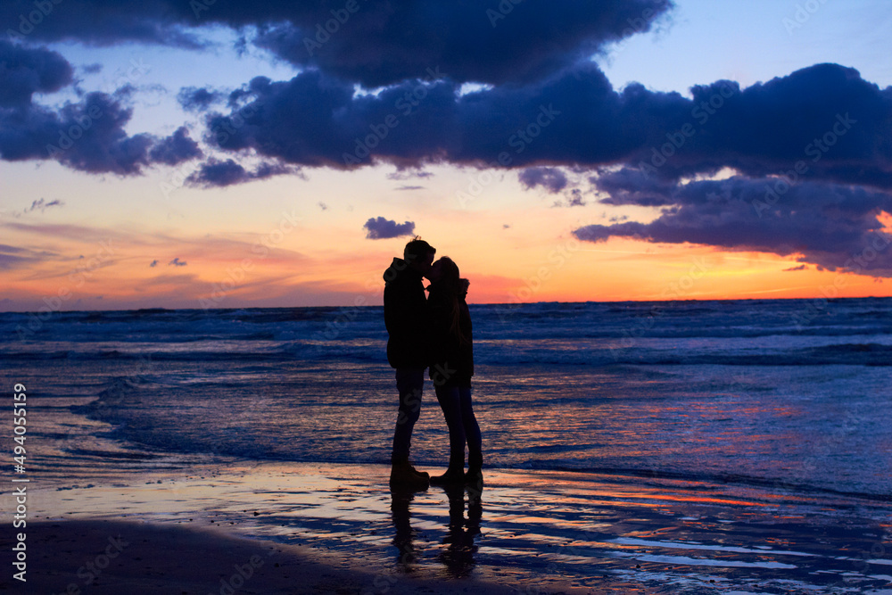 Nature setting the scene for romance. Silouehette of a couple kissing on the beach at sunset.