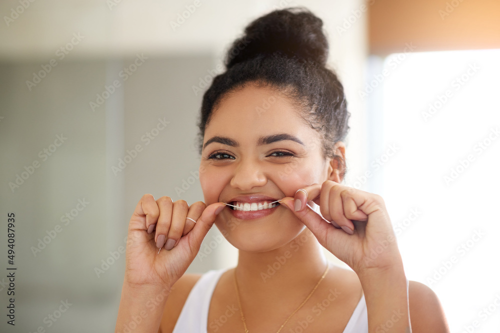 健康的习惯，健康的牙齿。一个迷人快乐的年轻女人用牙线洁牙的照片。