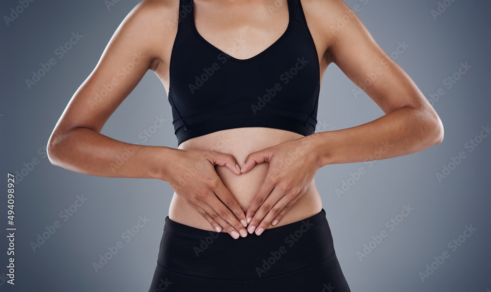 Shes in love with every curve on her body. Studio shot of a sporty young woman standing against a gr