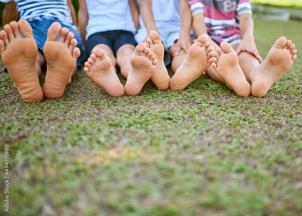 Your feet will take you to where the fun is. Cropped shot of a group of kids sitting barefoot on gra