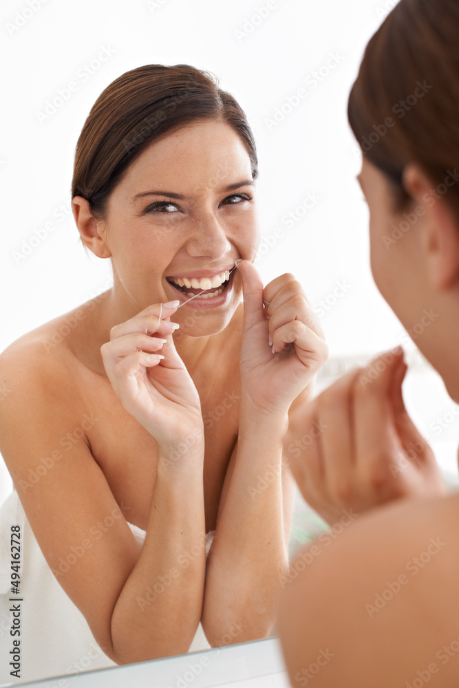 Keeping her mouth healthy and clean. Portrait of an attractive young woman flossing her teeth.