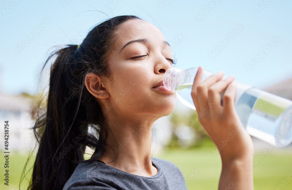 水的味道永远不会比流汗后更好。一名年轻女子在h后喝水的照片