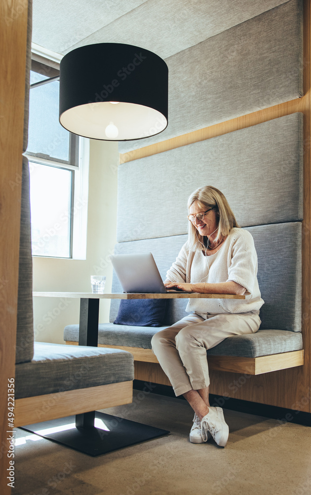 Mature businesswoman listening to music while working