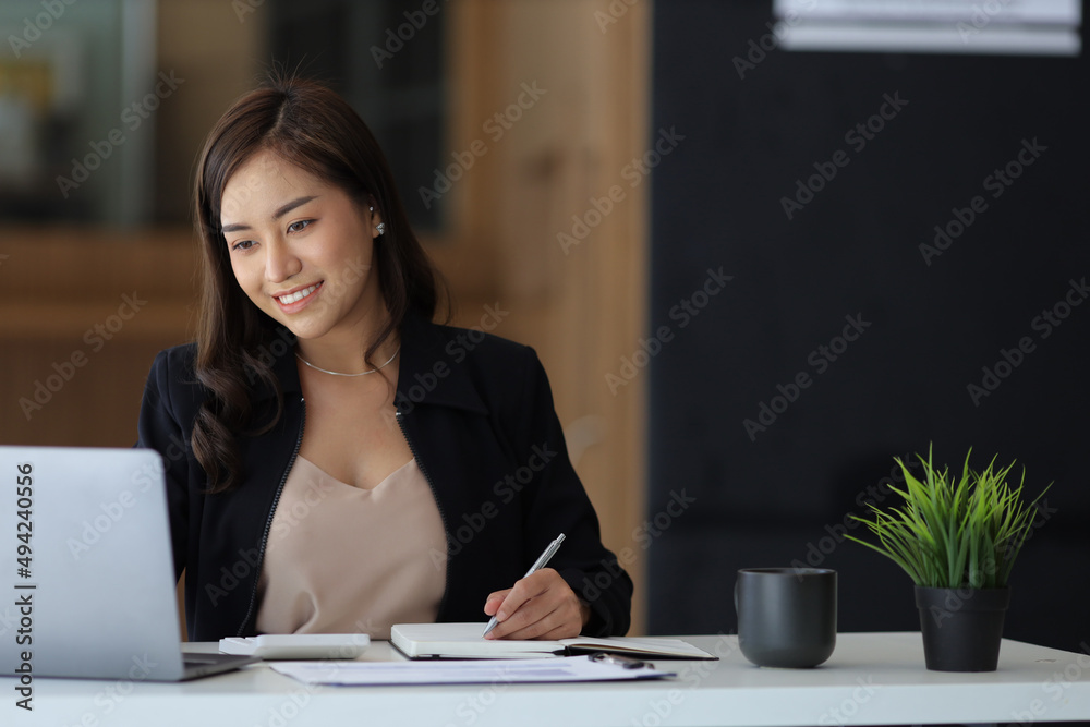 财务会计或女秘书使用笔记本电脑，并在笔记本上写日记。