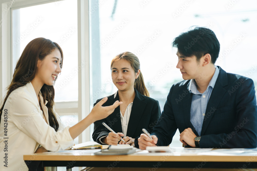 Great business meeting. Three Asian coworkers discussing something with smile while sitting at the o