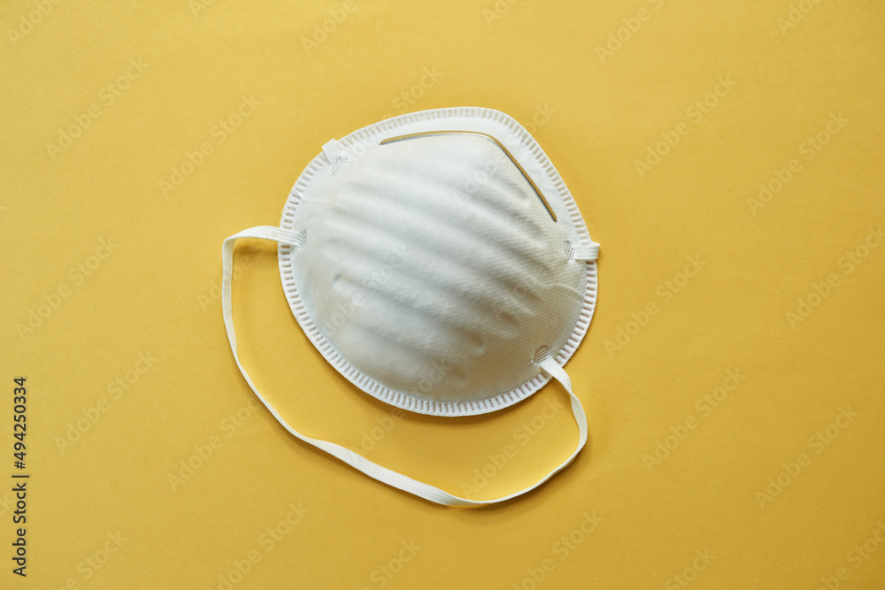 Dont leave home without it. Studio shot of a protective face mask against a yellow background.