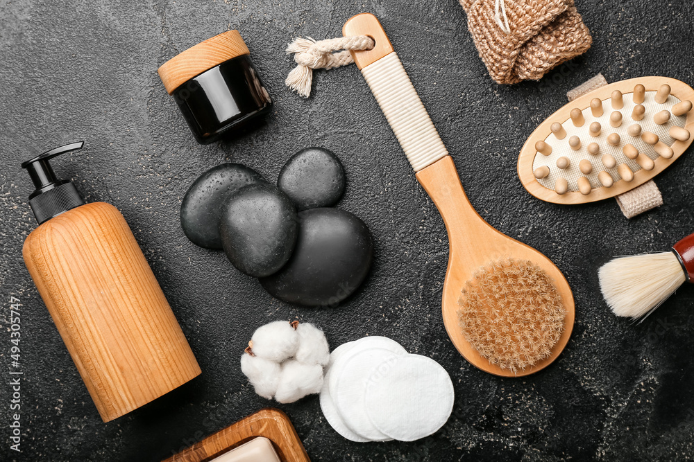 Bathing supplies with cosmetics and spa stones on dark background