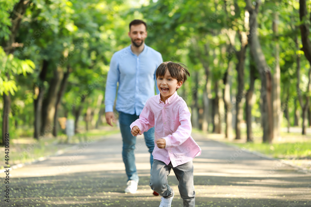 快乐的小男孩在公园里从父亲身边跑出来