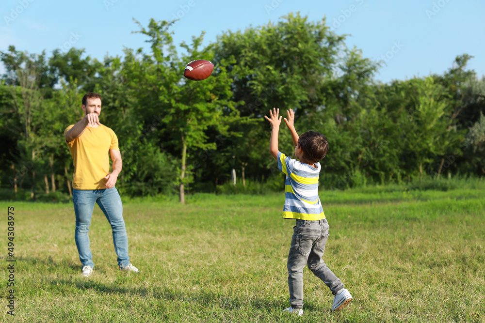 Father playing rugby with his little son on field