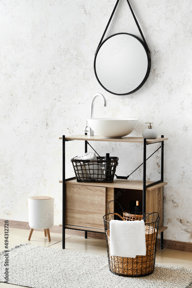 Interior of light bathroom with sink, baskets and mirror