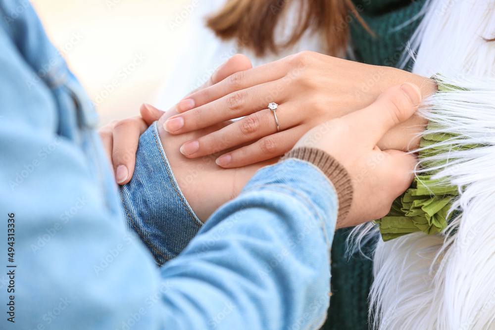 戴着订婚戒指的年轻女子和她的未婚夫在户外，特写镜头