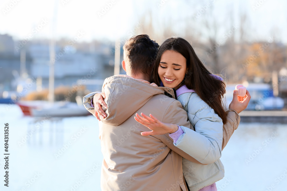 幸福的年轻女子在河边求婚后，带着订婚戒指拥抱未婚夫