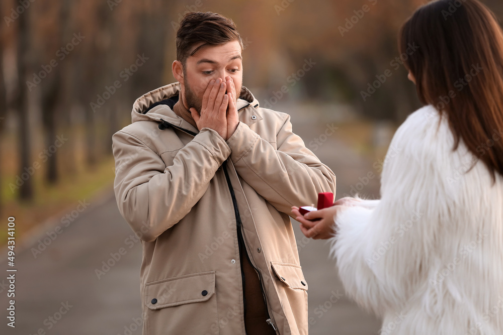 年轻女子在公园向她惊讶的男友求婚