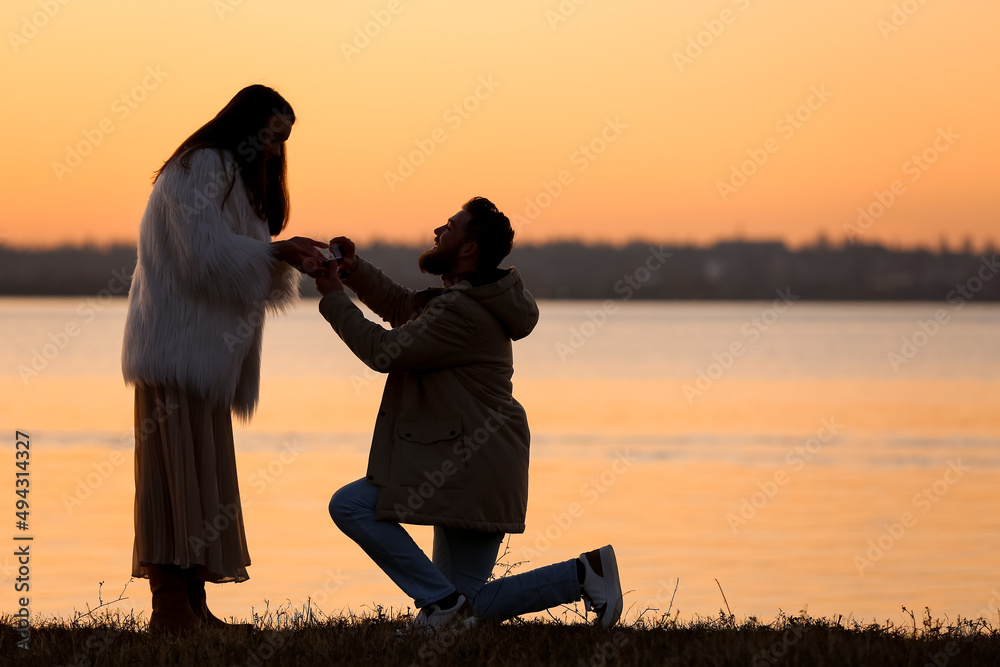 日落时分，一名年轻男子在河边向女友求婚