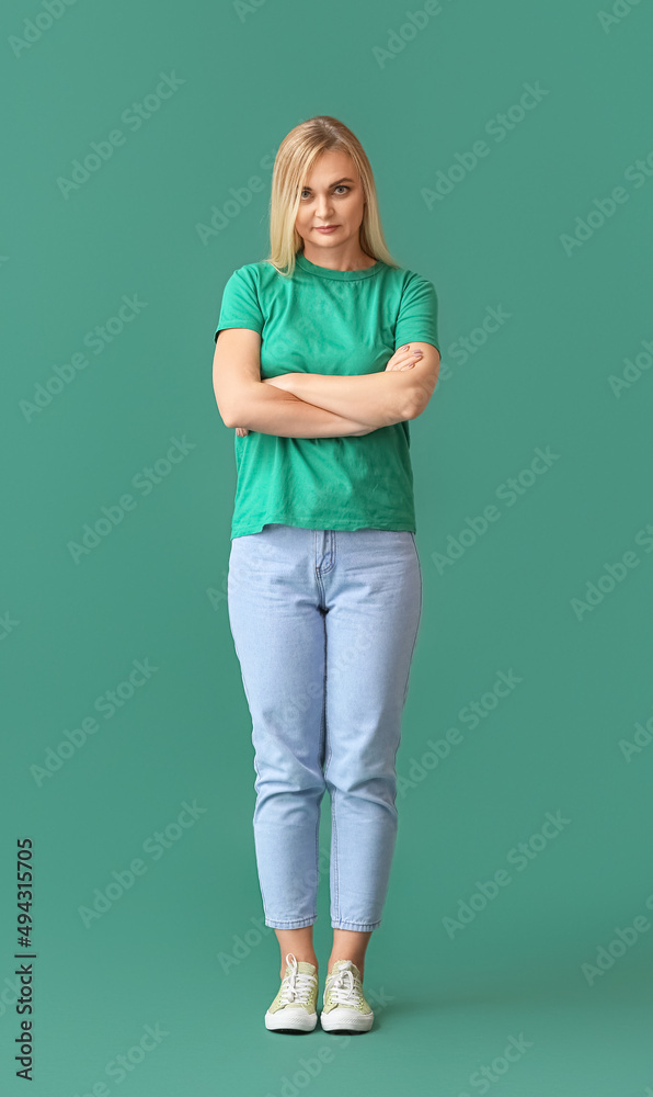 Beautiful blonde woman with crossed arms on green background