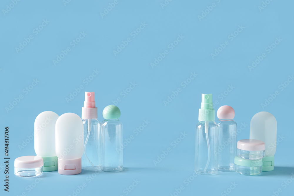 Set of empty travel cosmetic bottles and jars on blue background