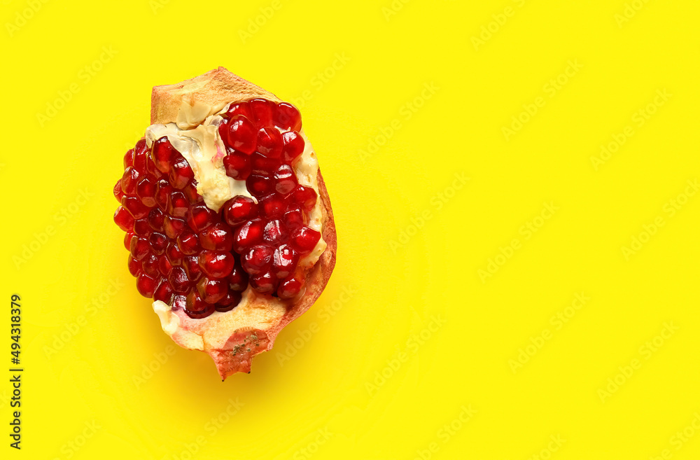 Tasty ripe pomegranate piece on yellow background